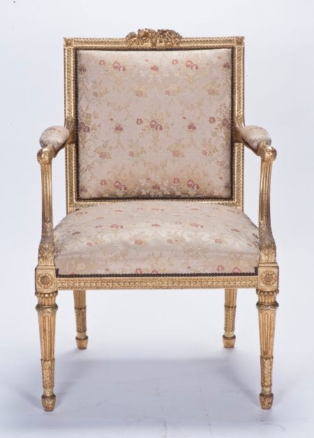 A gilded carved arm chair with a square seat and back, upholstered in white damask.