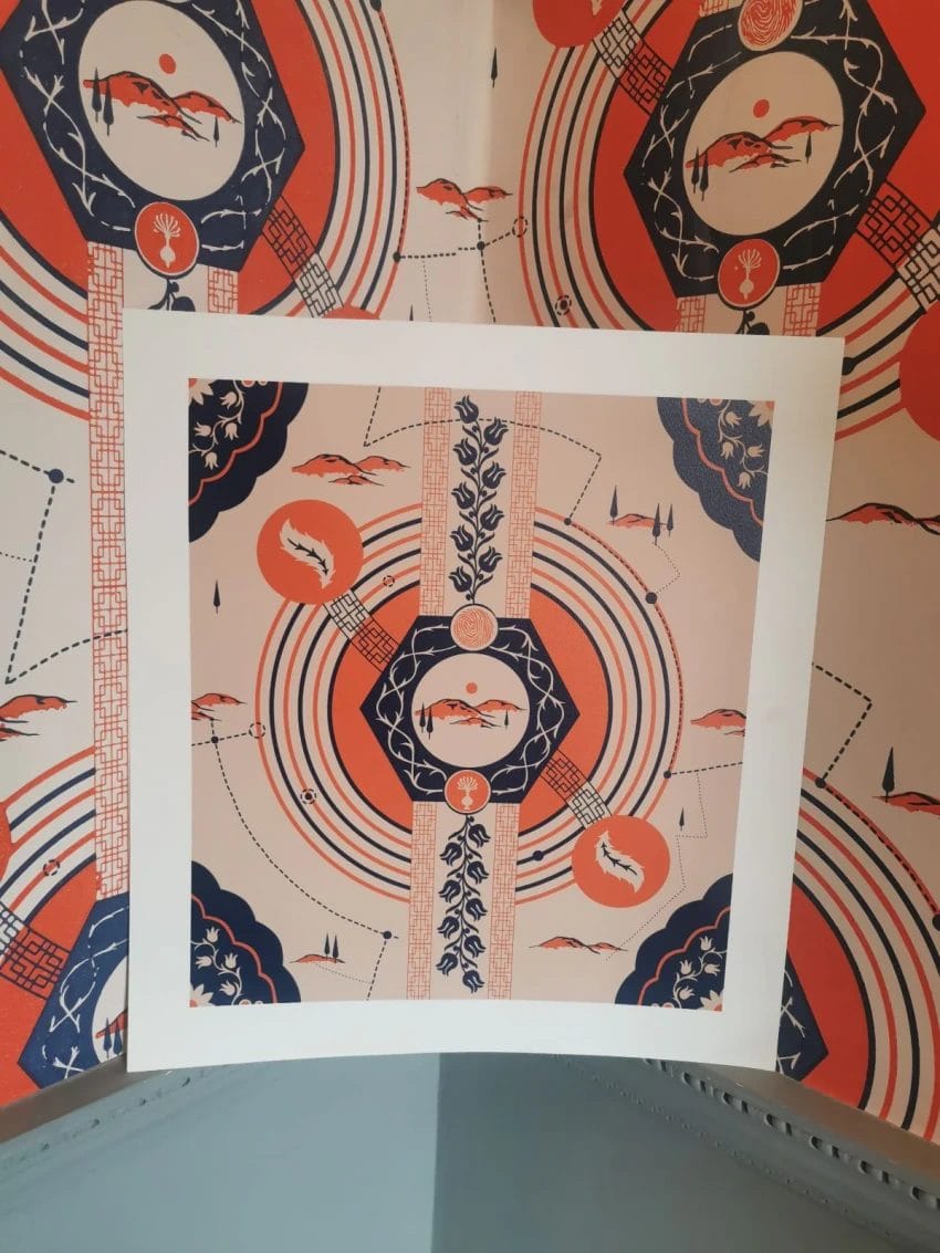 A square print of a section of Mani Kambo's wallpaper which features motifs found in the details of Harewood Collection. The print is a mix of reds and blue.