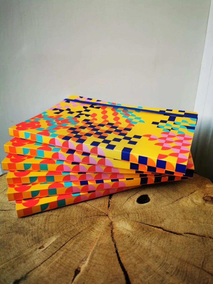 A pile of colourful notepads on top of a log table.