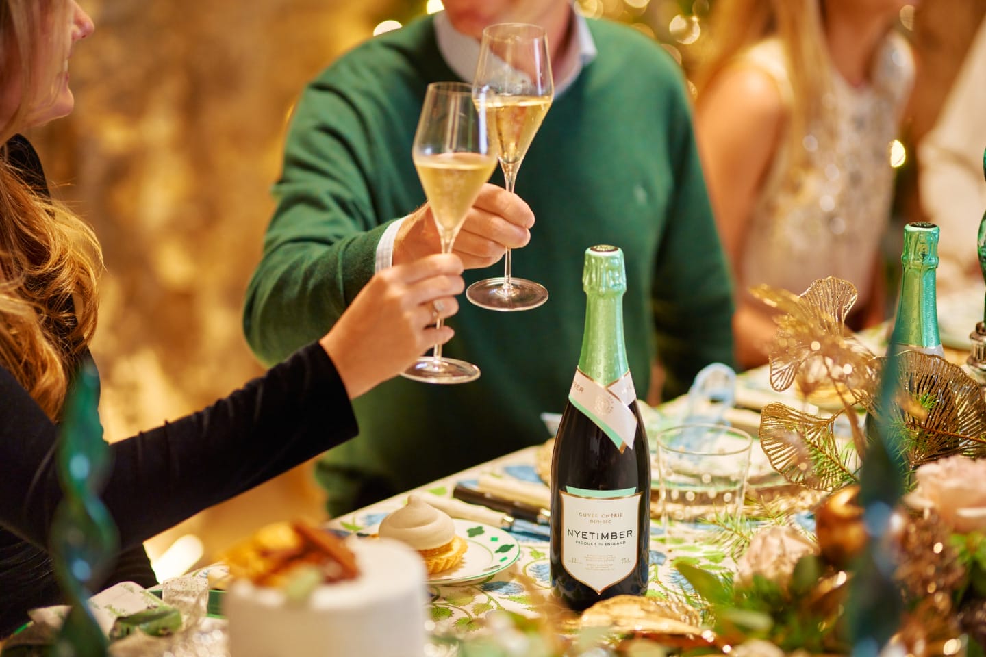 Two people raise a toast with glasses of wine in hand at a decorated table.