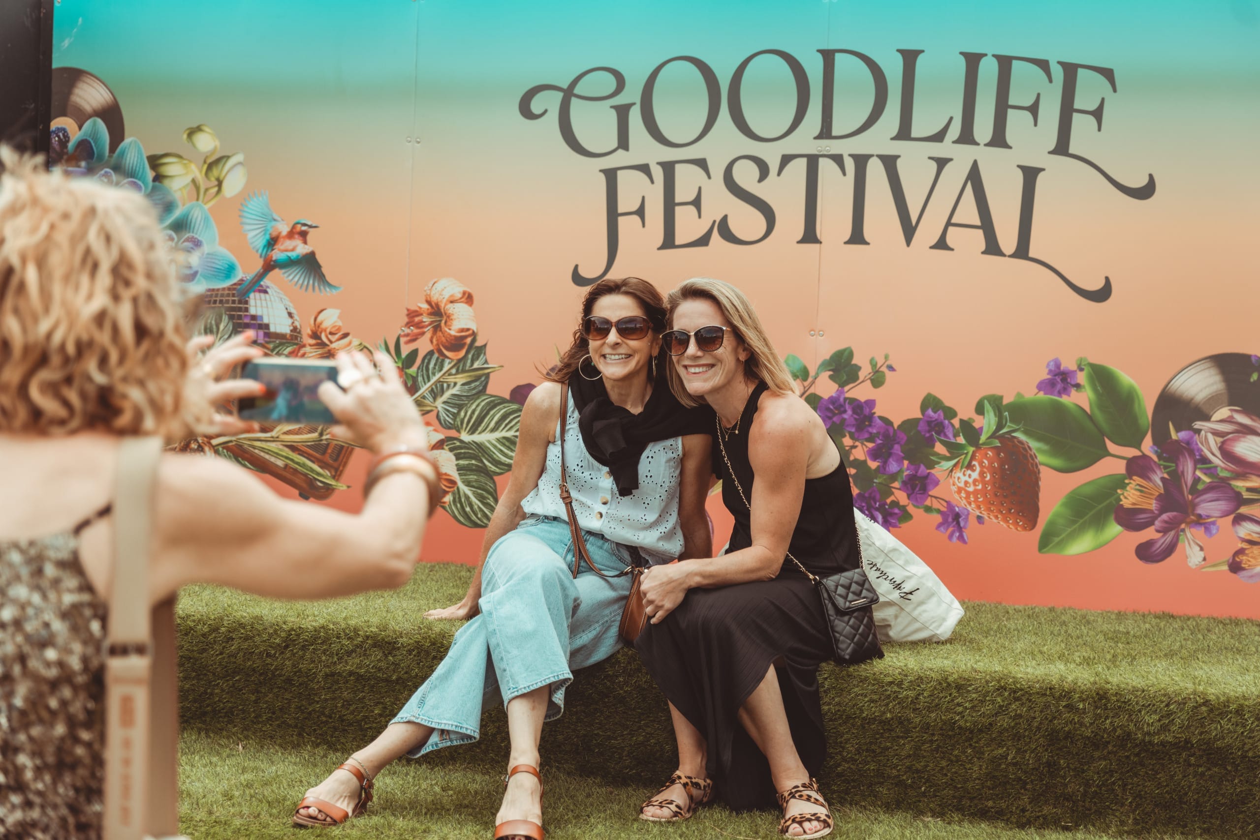 Two women pose for a photo in front of a Goodlife Festival banner.