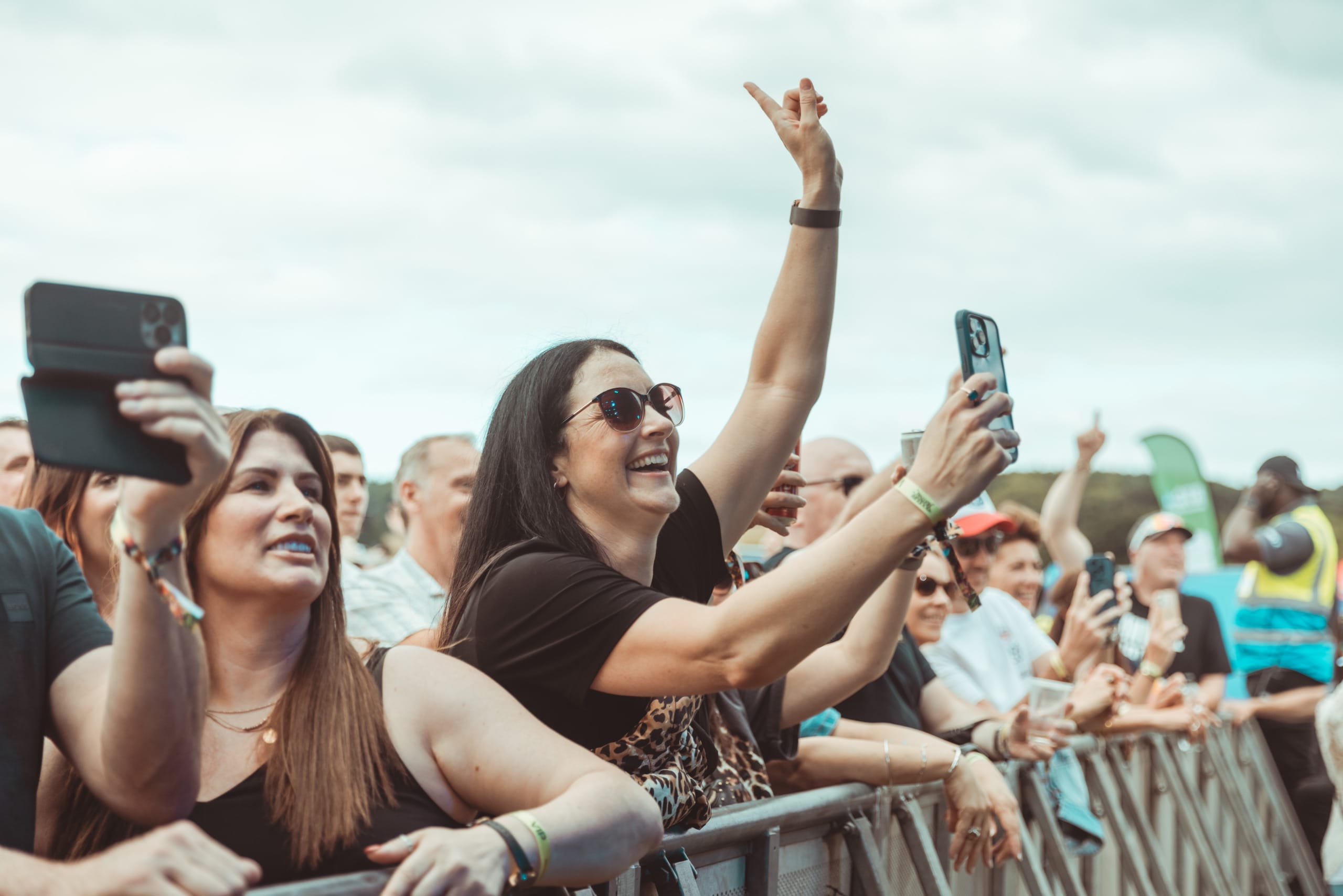 A woman at a concert filming an act on her phone.
