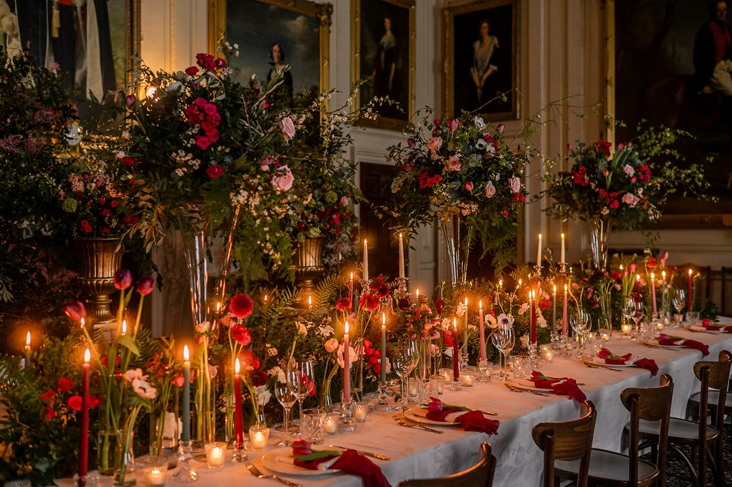 A long dining table adorned with candles and a floral centerpiece, creating an elegant atmosphere.
