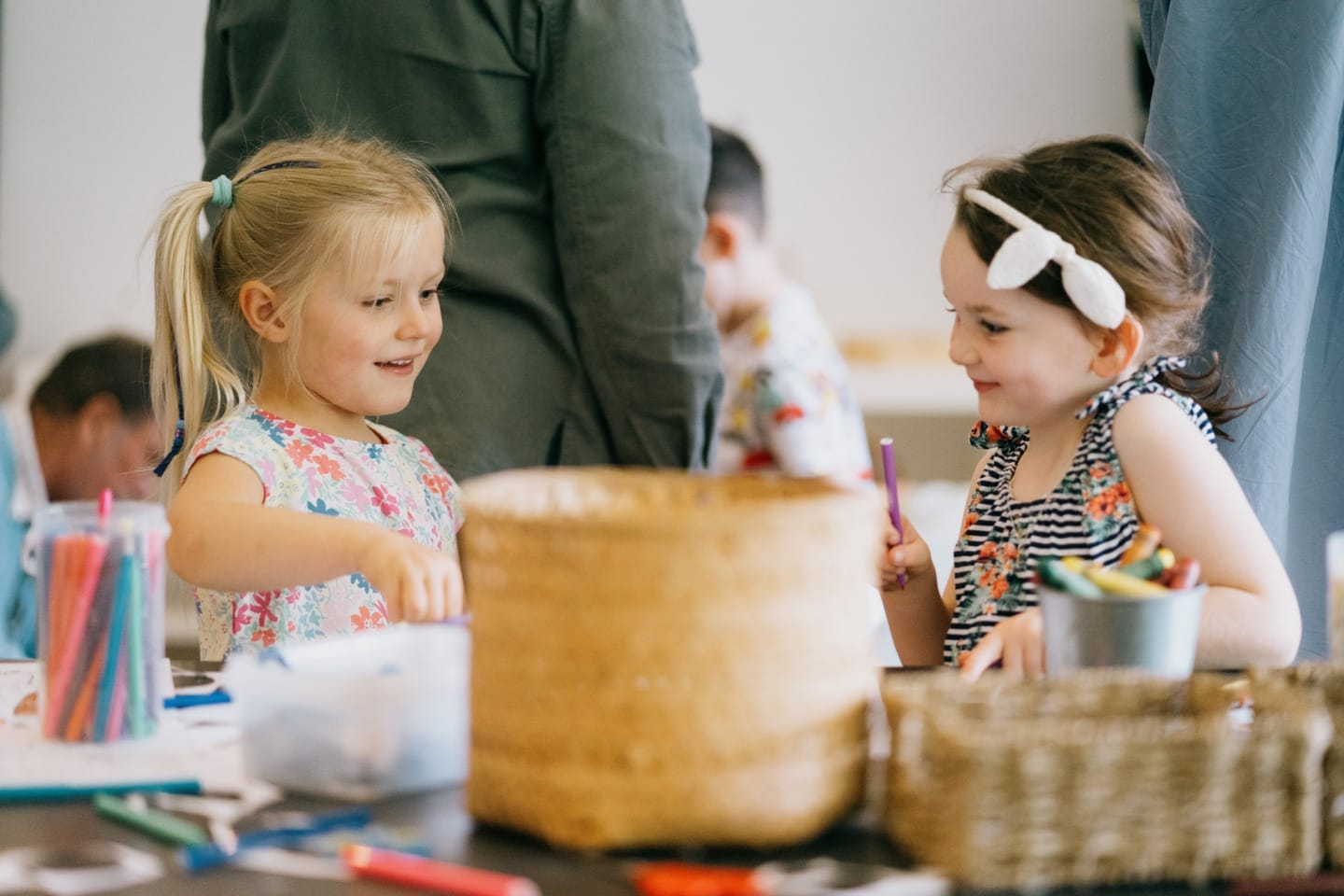 Two young children doing flower-themed crafts together at a table with coloured pencils and craft materials.
