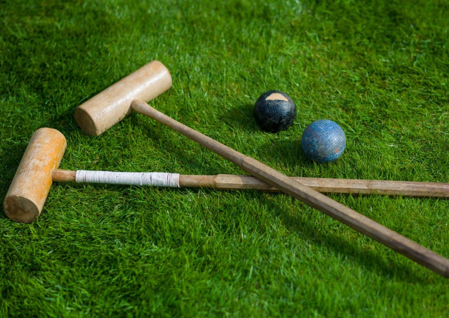 A wooden croquet set placed down on grass.